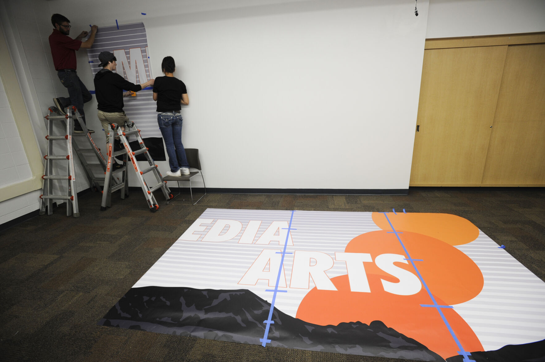 Workers from Allegra Print hang a vinyl i